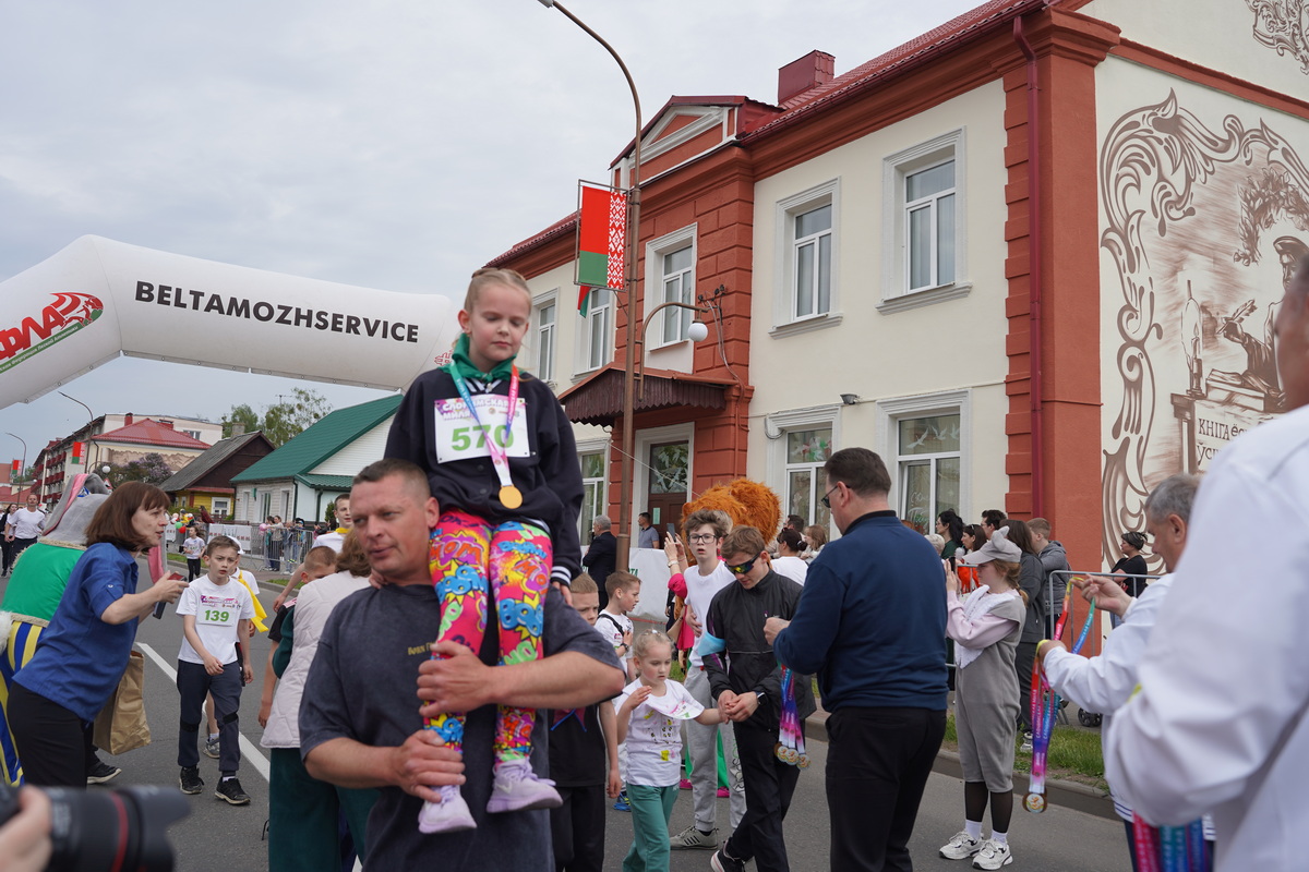 Участники семейного забега после финиша получают памятные медали.