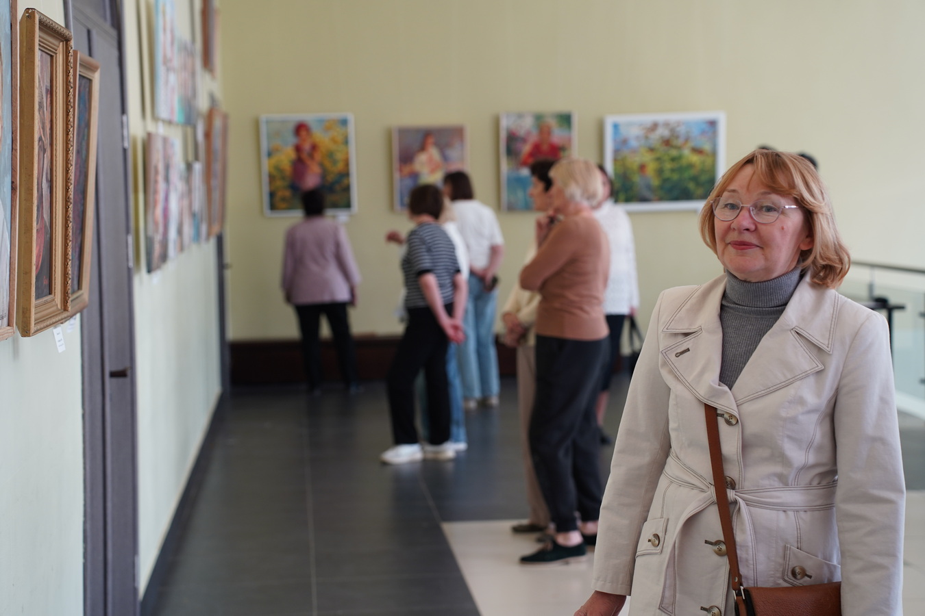 Женщина стоит в выставочном зале на фоне посетителей